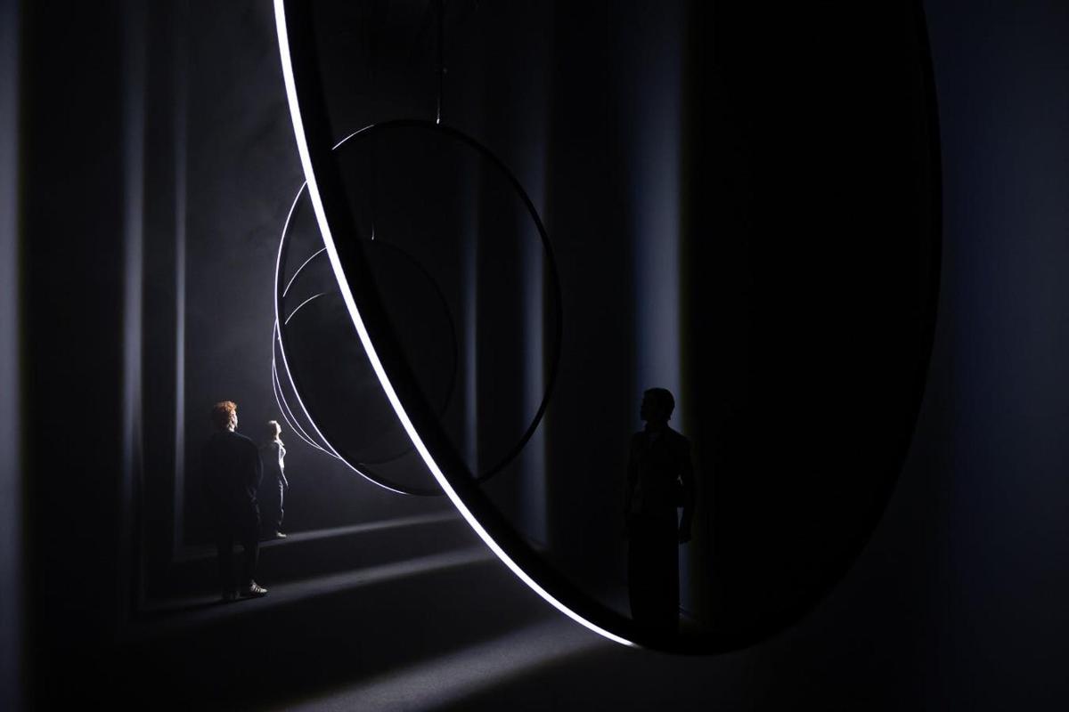 two people standing in front of a large mirror