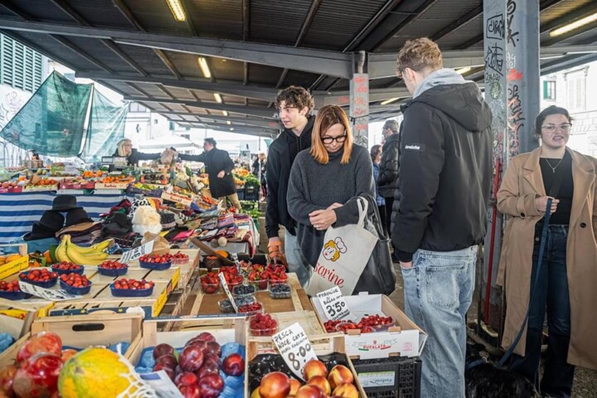 Un grupo de personas de pie alrededor de un mercado con frutas y verduras.