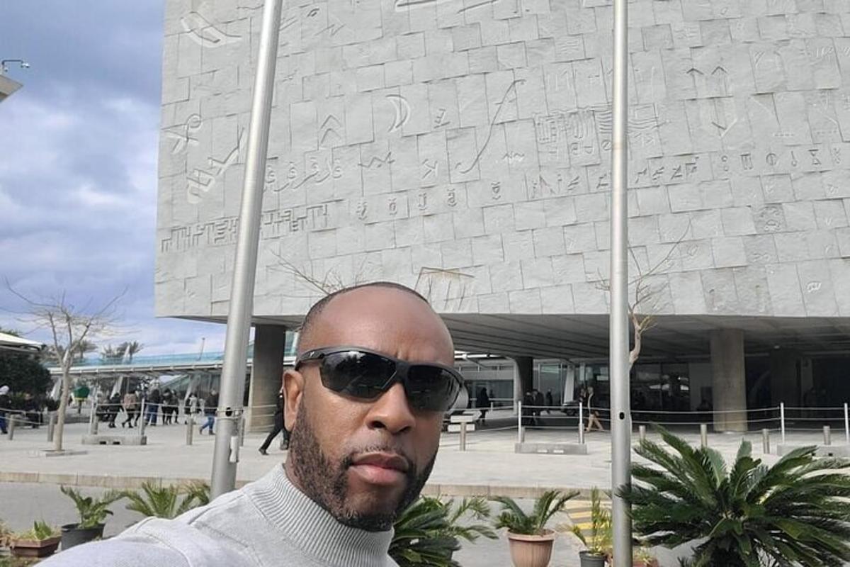 a man wearing sunglasses standing in front of a monument