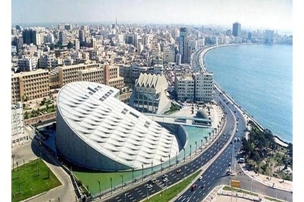 a large white building in a city next to the ocean
