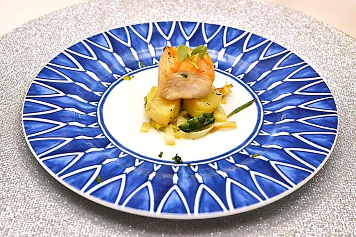 um prato azul e branco com um pedaço de peixe e vegetais