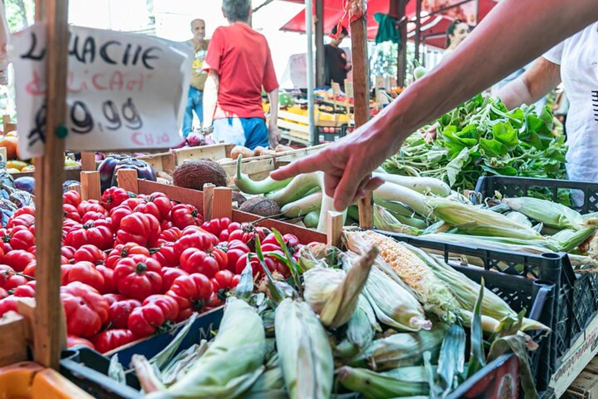 eine Person, die auf einem Bauernmarkt nach Gemüse greift