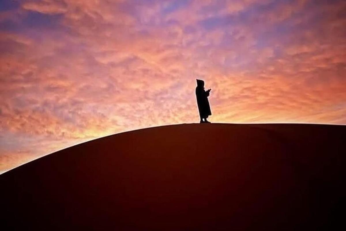 a man standing on top of a hill at sunset