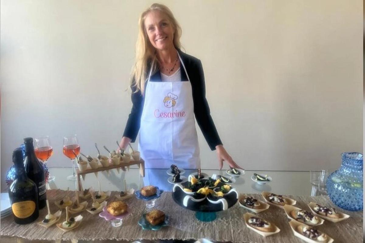 una donna con un grembiule in piedi accanto a un tavolo con del cibo