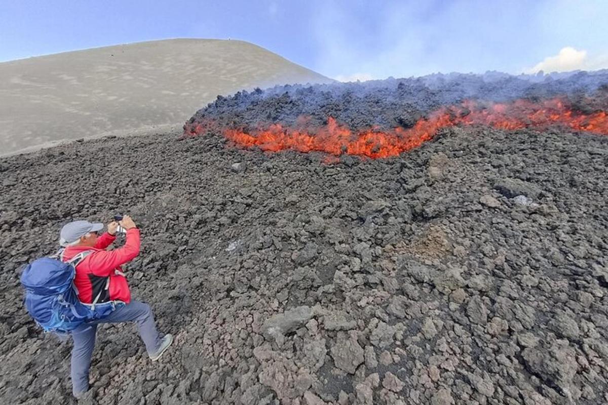 a man taking a picture of a lava eruption