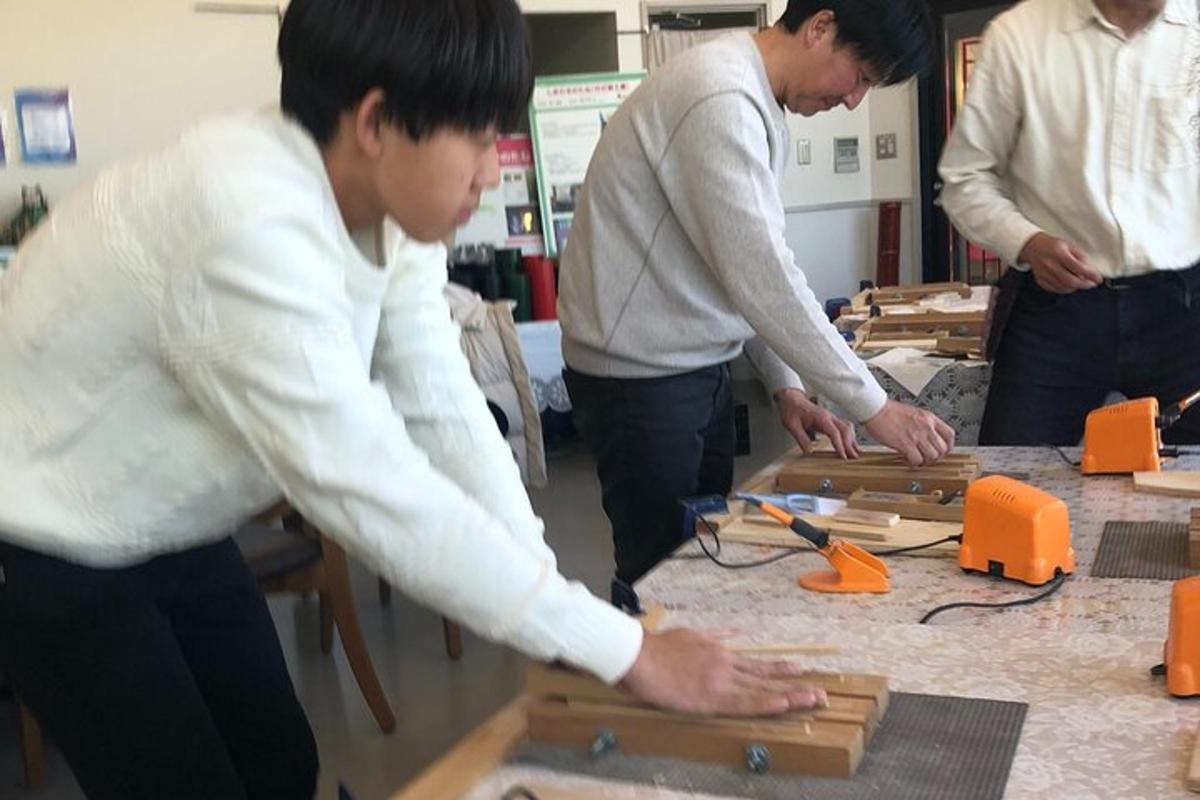 a group of people standing around a table cutting wood