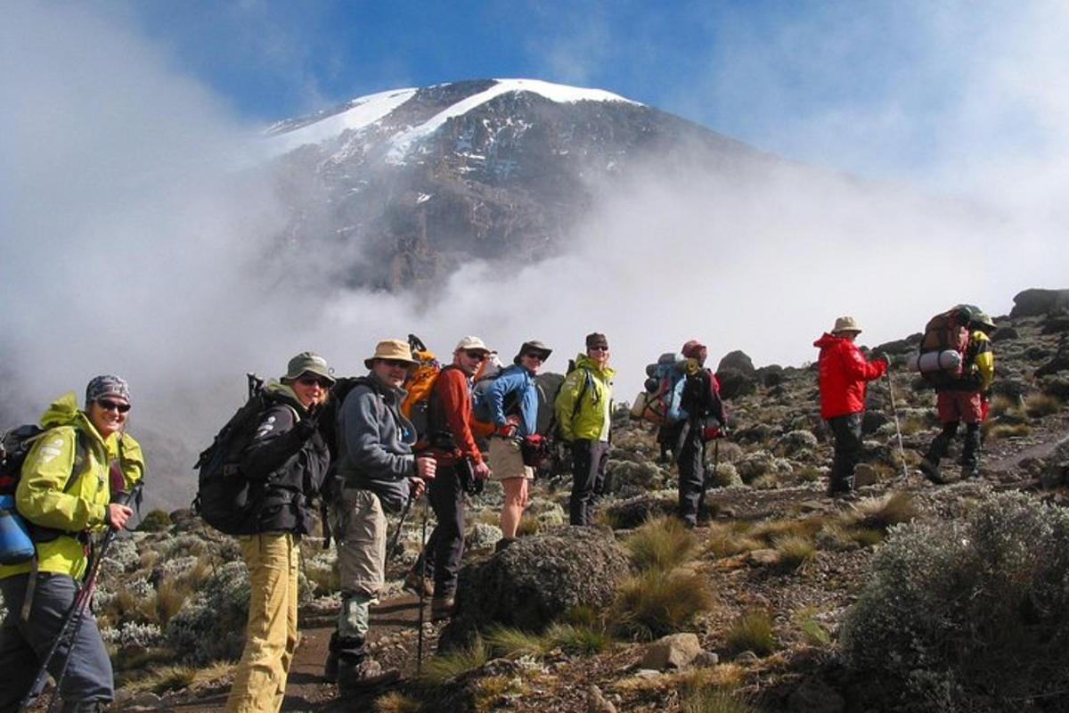 sekumpulan orang berjalan di atas gunung dengan gunung yang dilitupi salji
