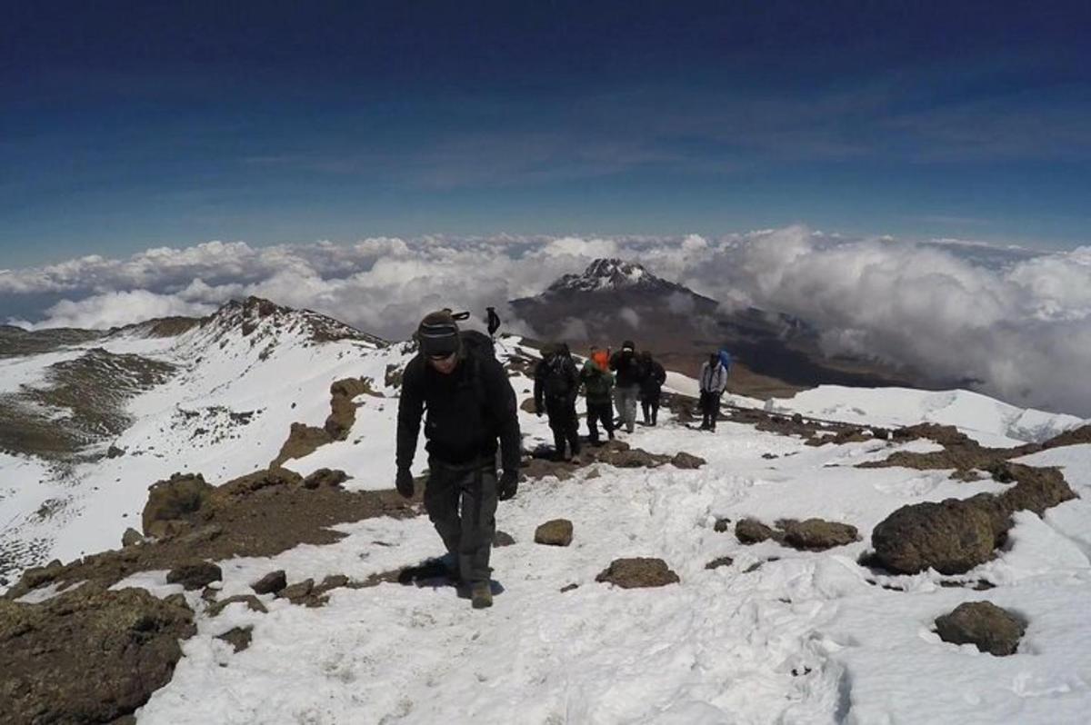 sekumpulan orang berjalan di atas gunung yang dilitupi salji
