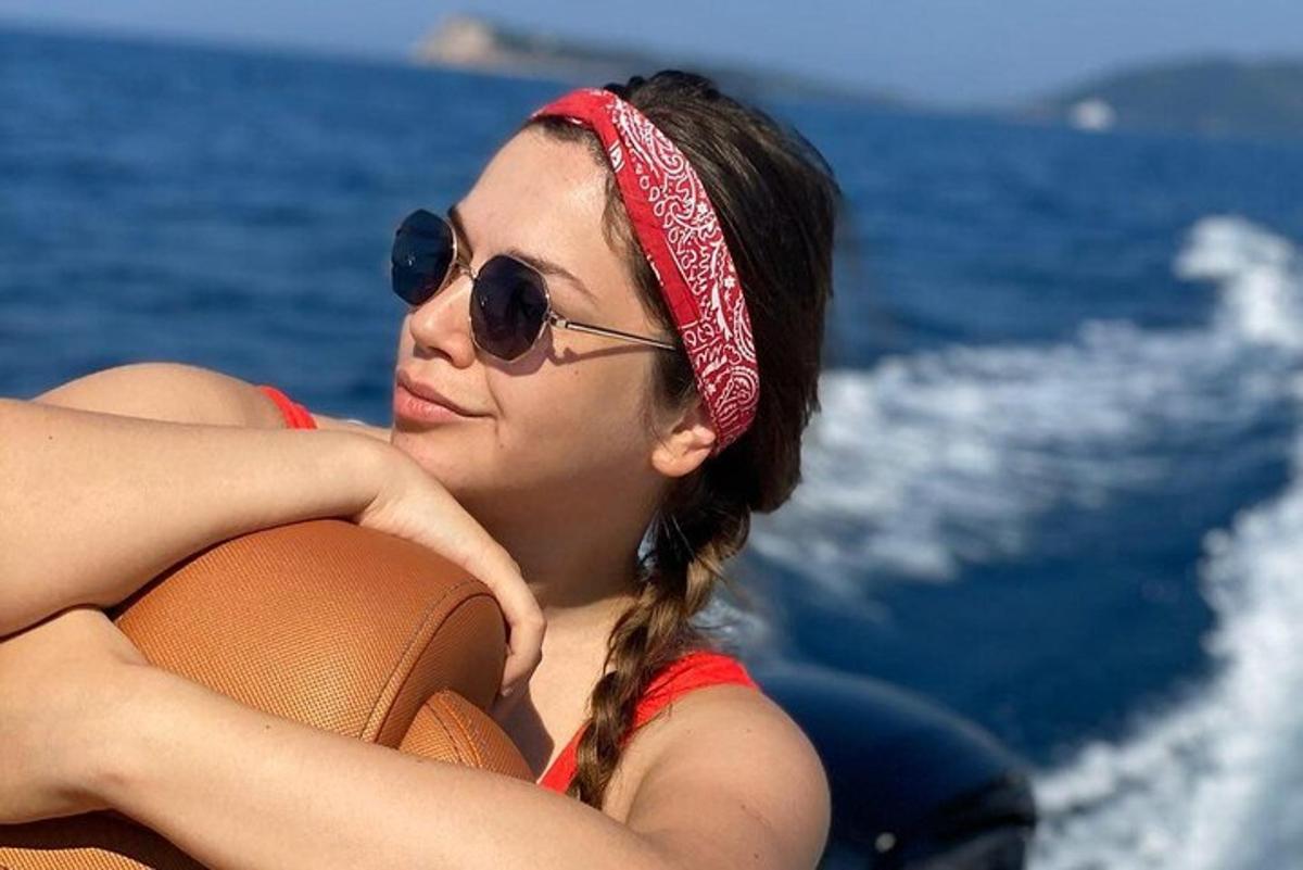 una donna che indossa occhiali da sole e una fascia rossa sdraiata su una barca