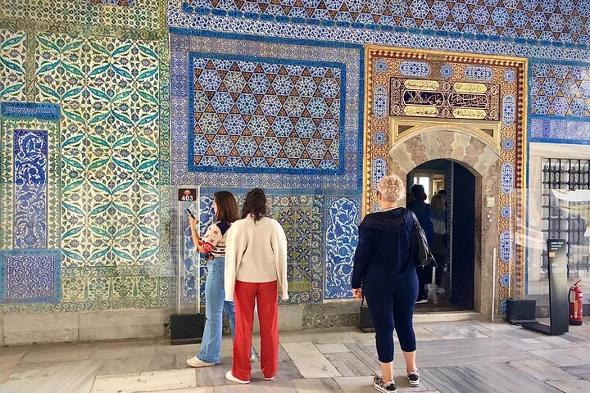 Un grupo de personas de pie frente a una pared de mosaico.