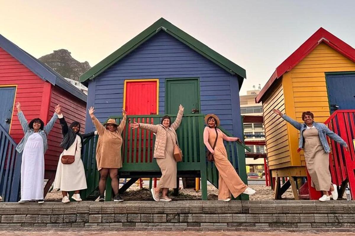 un gruppo di persone in piedi davanti a colorate cabine sulla spiaggia