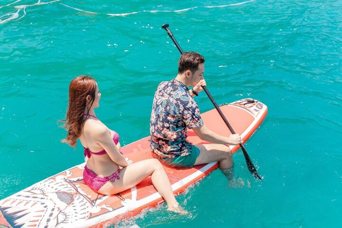 un uomo e una donna seduti su una tavola da paddle in acqua