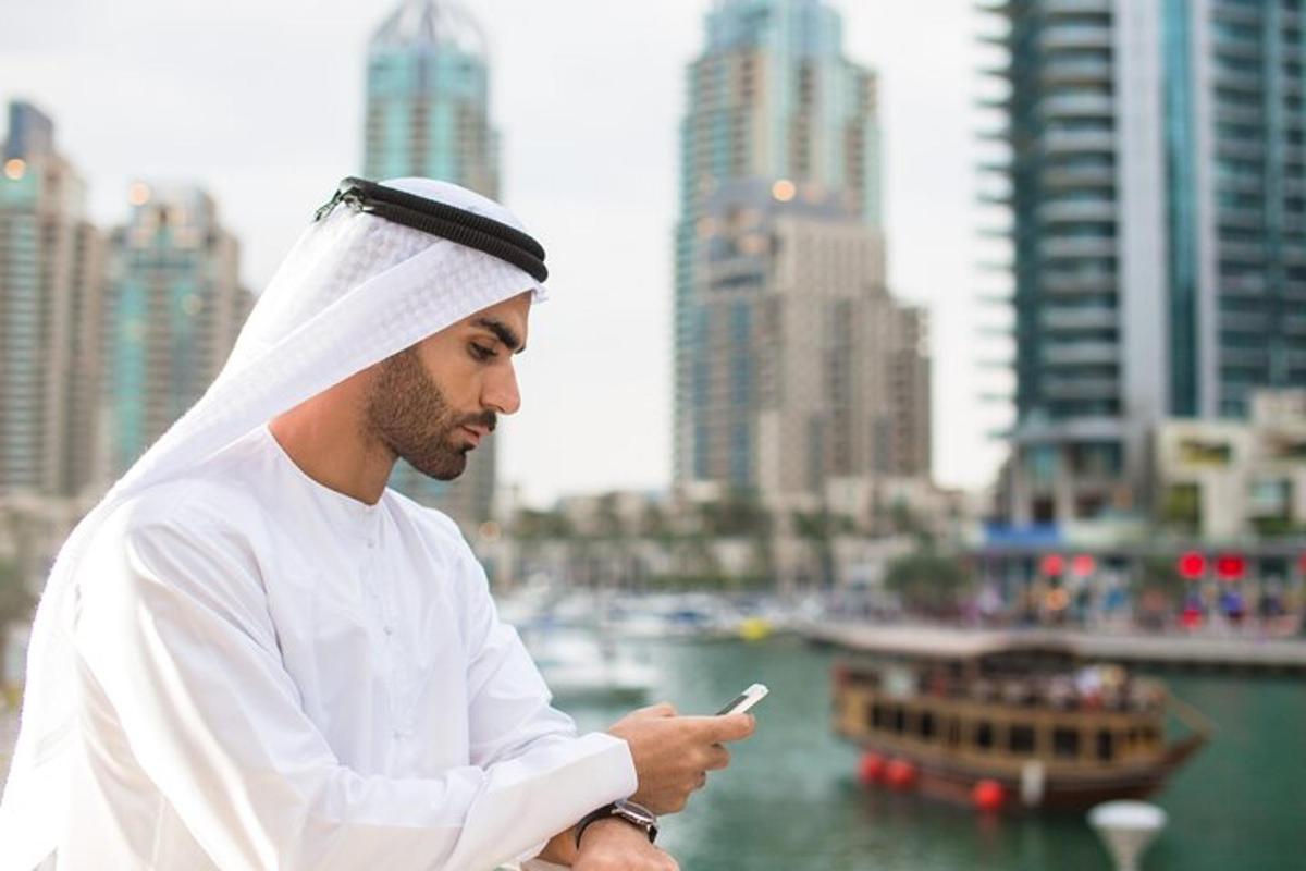 a man looking at his cell phone in front of a city
