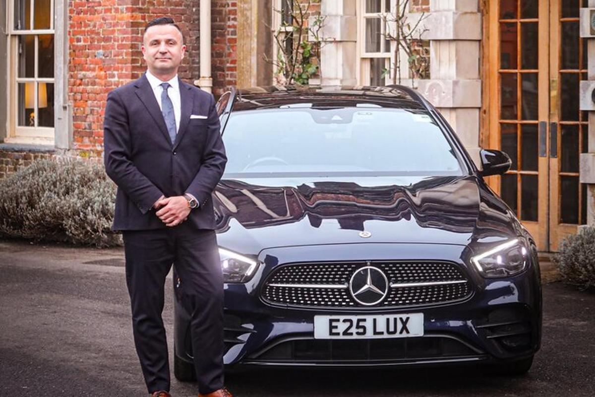 a man in a suit standing in front of a car