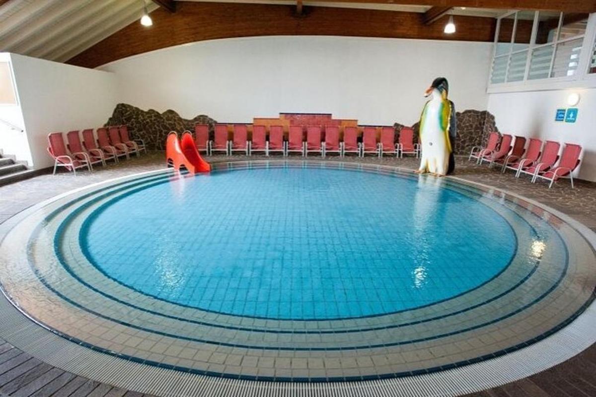 una grande piscina con sedie rosse e una donna in piedi accanto ad essa
