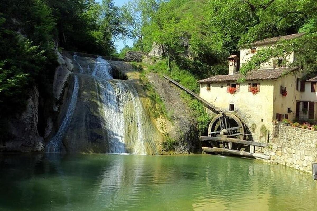 una cascada al costat d'un riu amb una roda hidràulica
