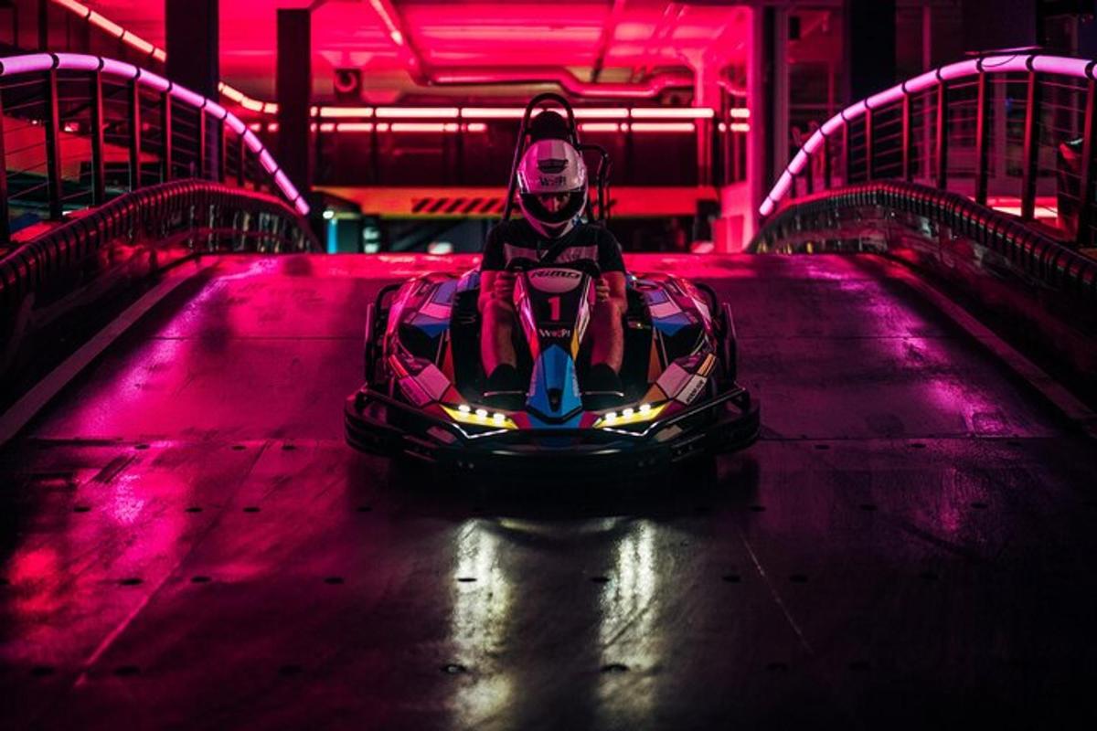 Una persona que conduce un coche de carreras en una pista con luces rosas.