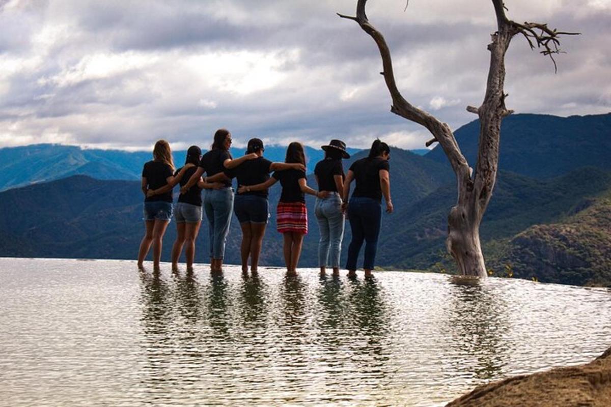 a group of people standing on the edge of a body of water