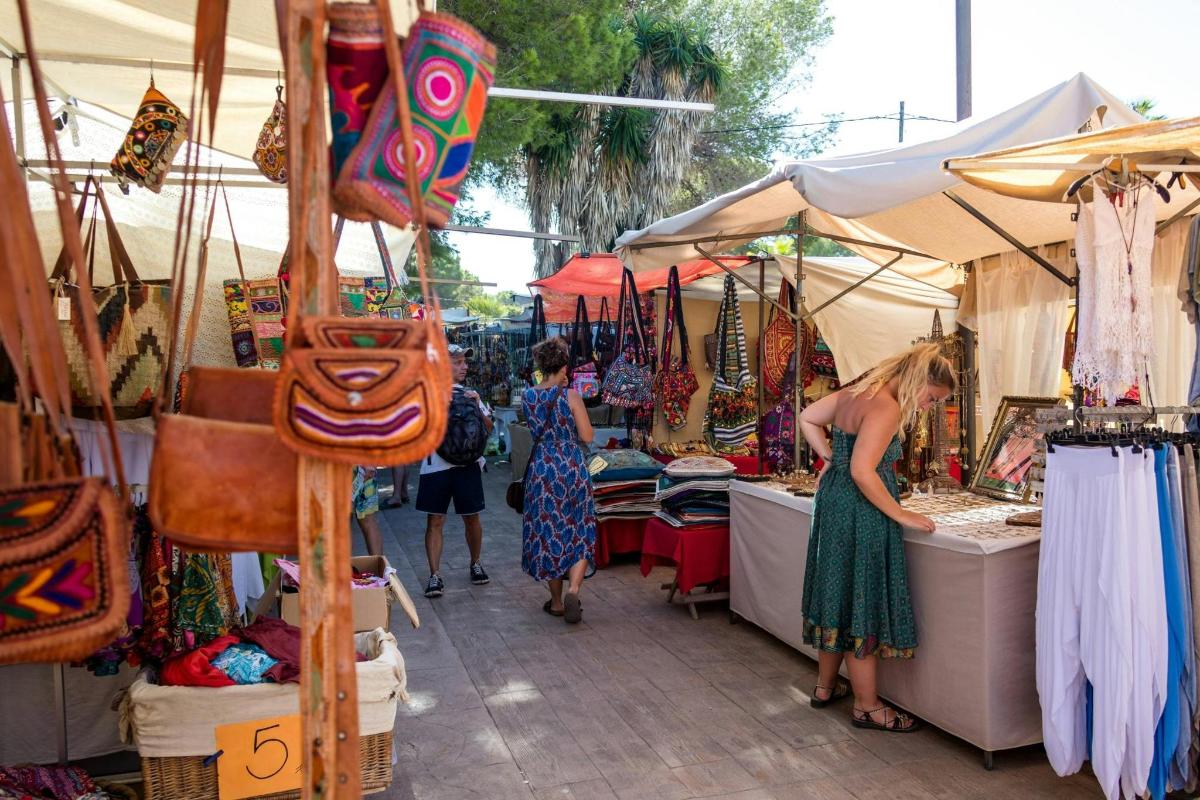 a group of people walking around a market with vendors