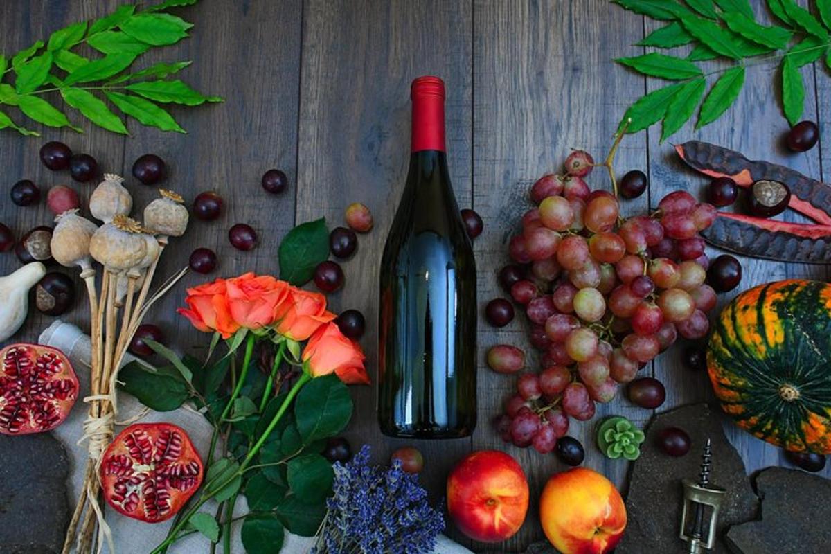 Una botella de vino sobre una mesa con frutas y verduras.