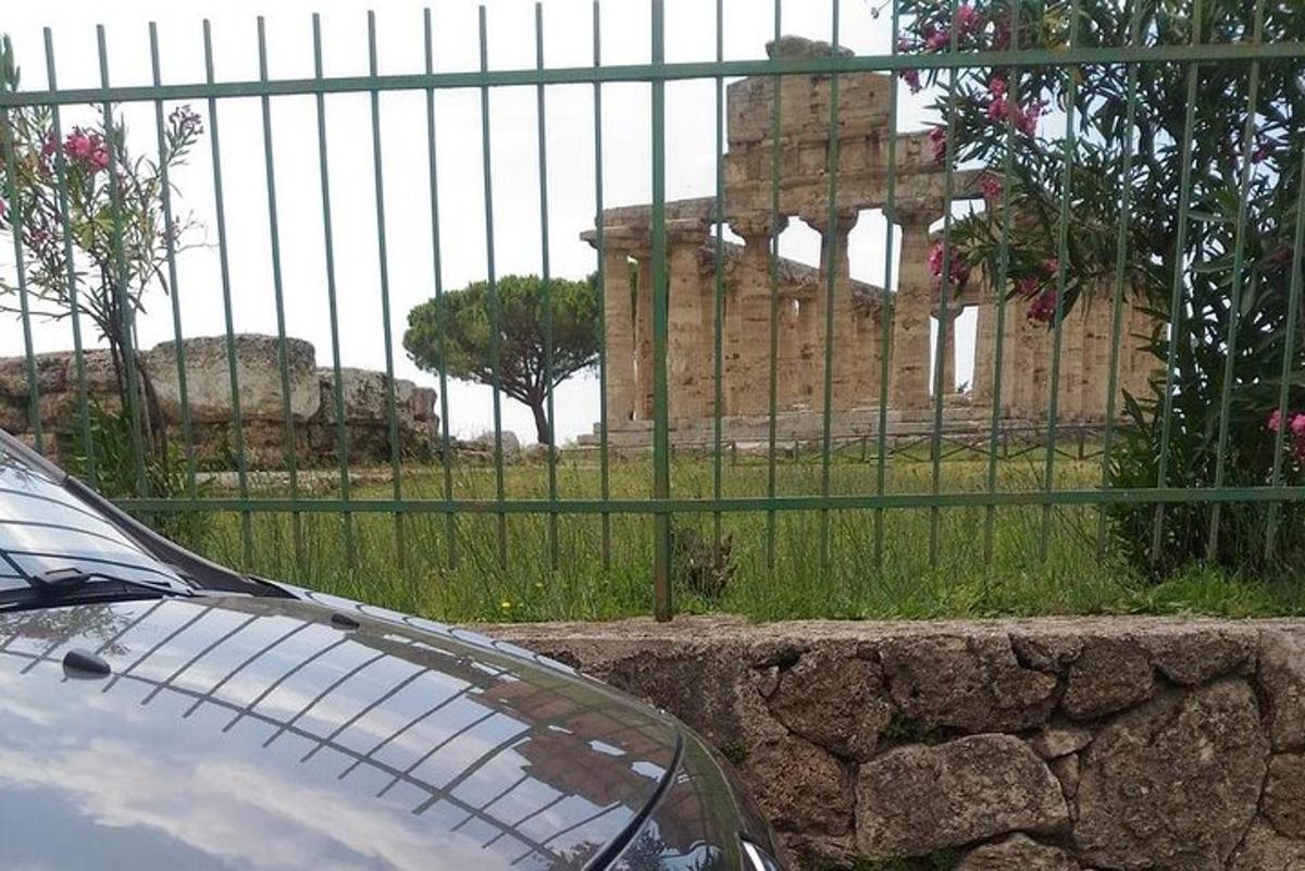 a car parked in front of a fence with a building