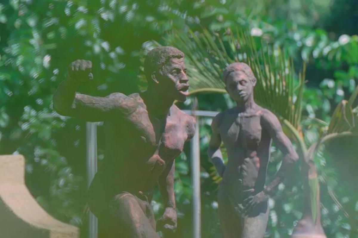 due statue di due uomini seduti su una staccionata