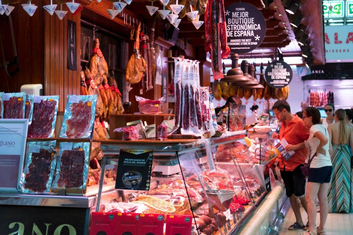 a group of people standing in a market selling meat