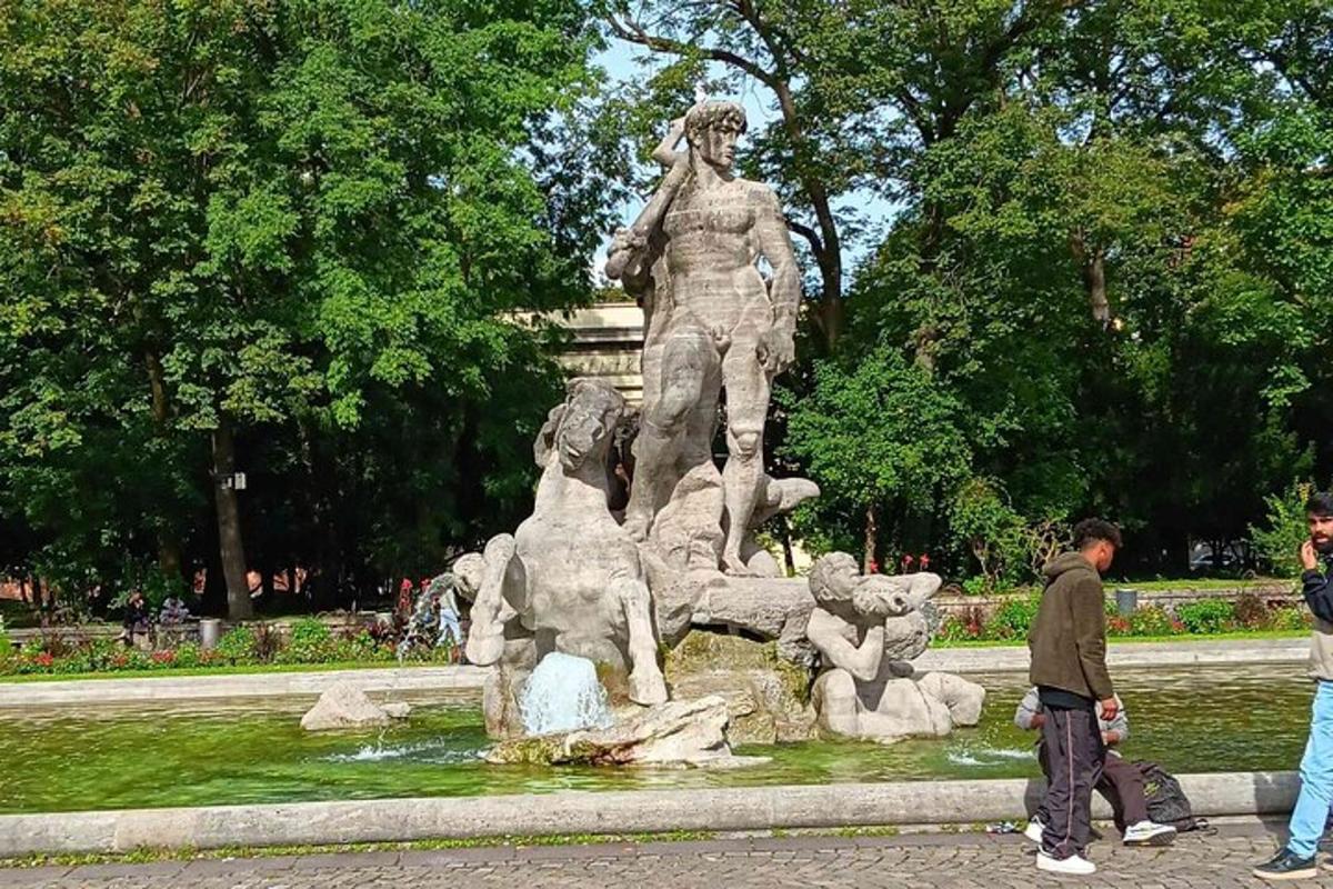 socha v parku, kolem které chodí lidé
