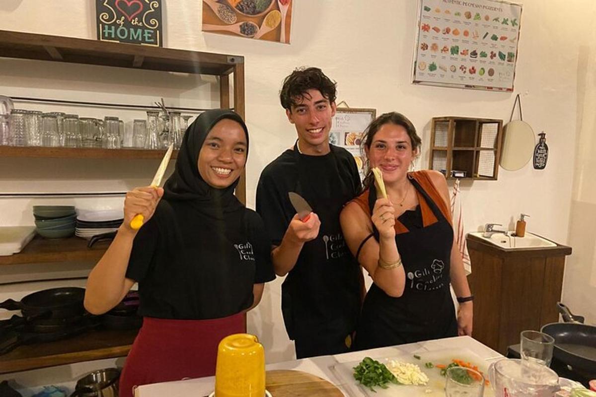 three people standing in a kitchen holding wooden utensils