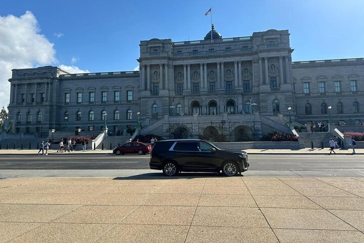 Un coche negro aparcado delante de un gran edificio.