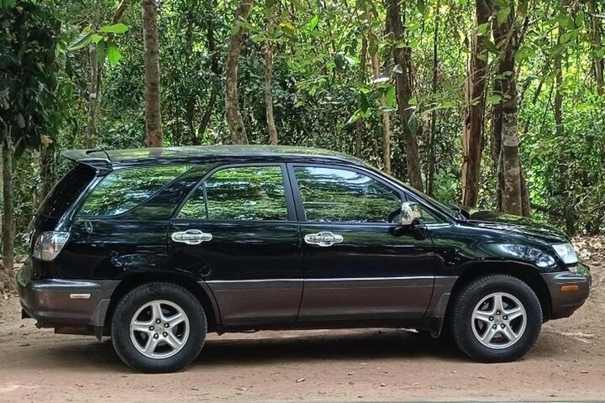 um carro preto estacionado em frente a uma floresta