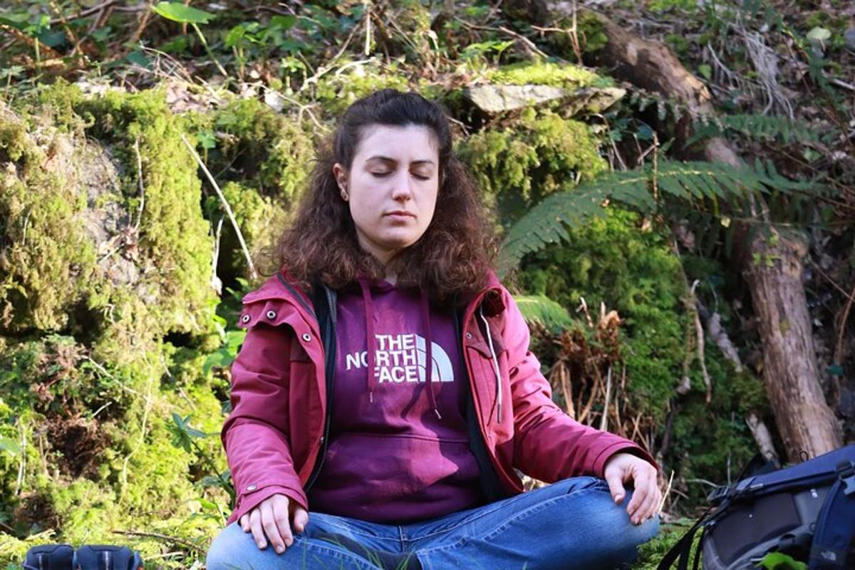 uma mulher sentada no chão da floresta