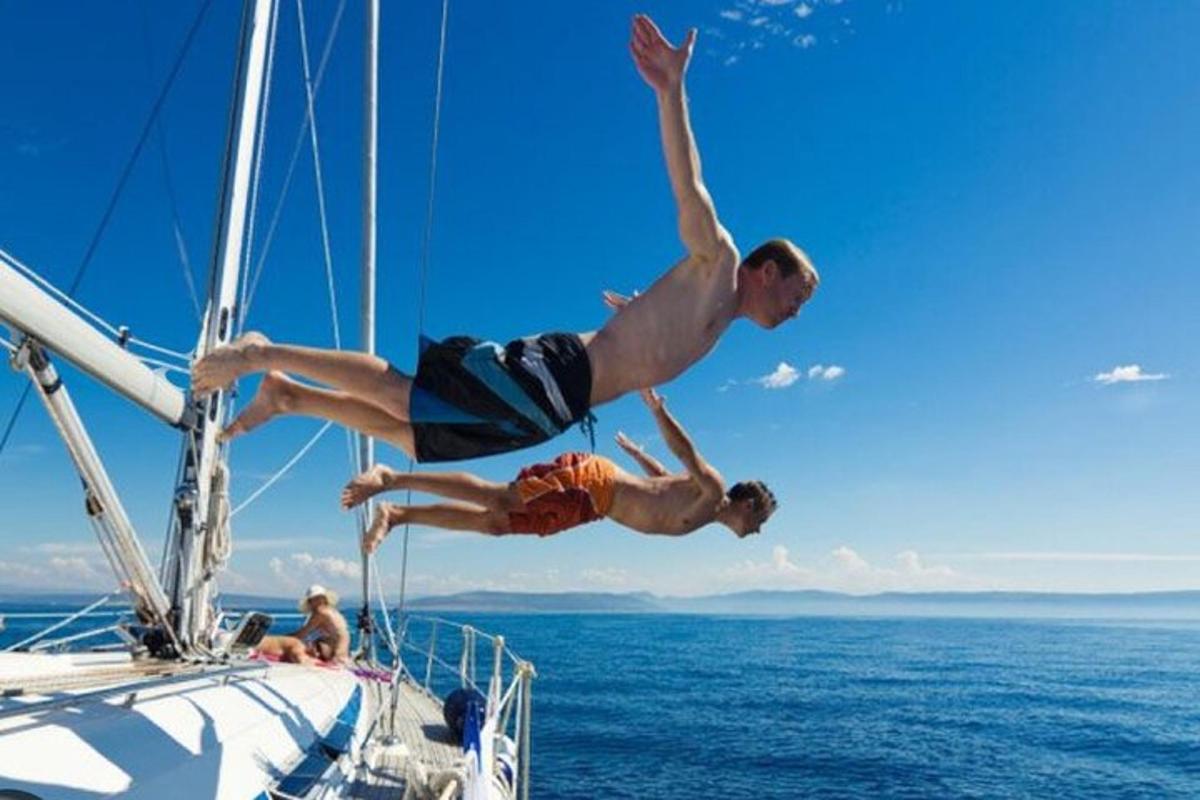 due uomini che saltano da una barca a vela