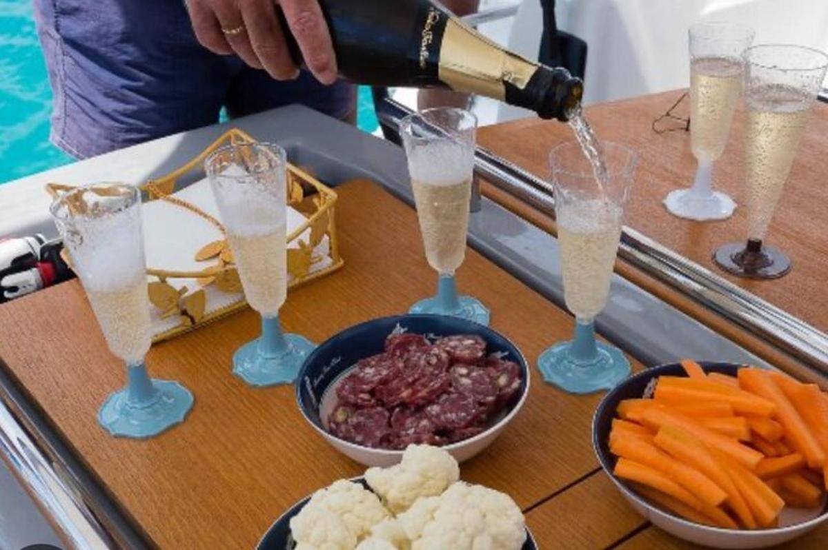 una persona che versa champagne nei bicchieri su un tavolo con del cibo