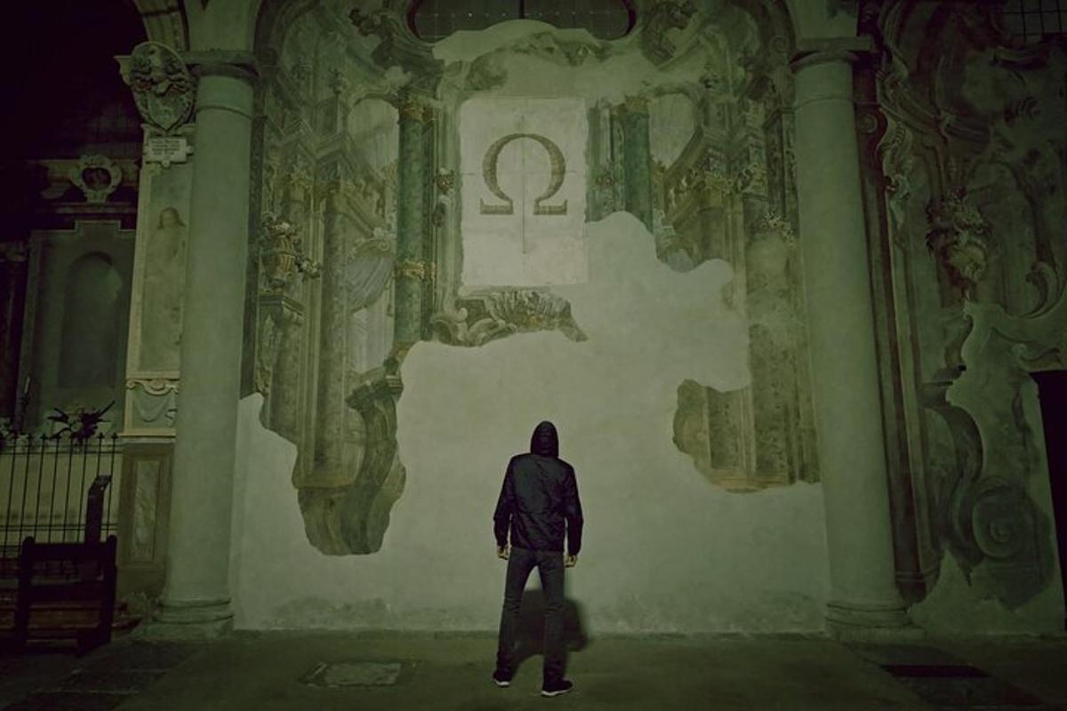 a man standing in front of a wall with a symbol on it