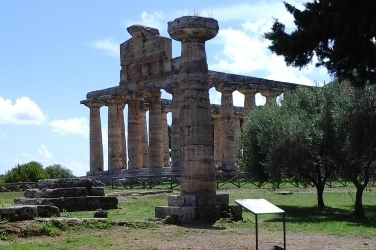 un antico edificio in un campo con un cartello di fronte