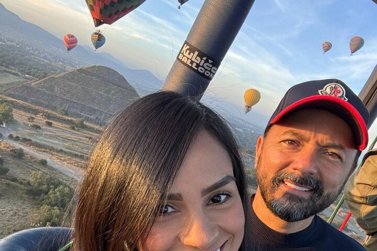 a man and a woman standing in front of some hot air balloons