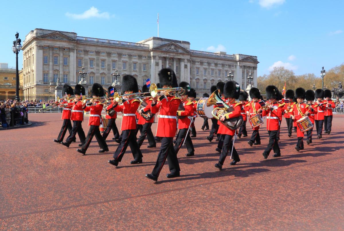 Una banda de música con uniforme rojo frente a un edificio