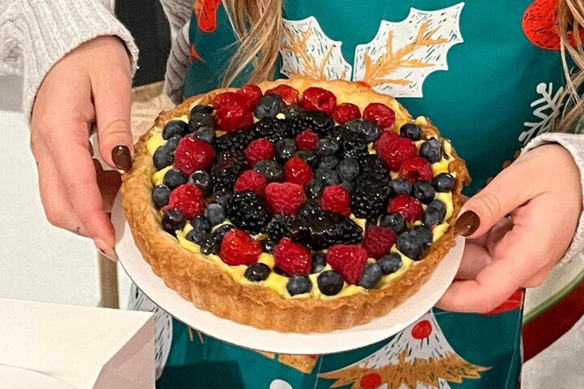 una persona che tiene in mano una torta con sopra delle bacche