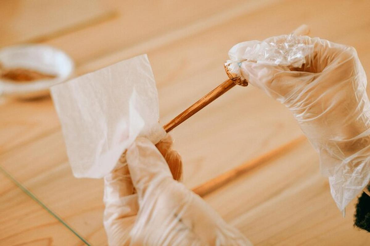 una persona con guantes de goma sosteniendo un palo de madera