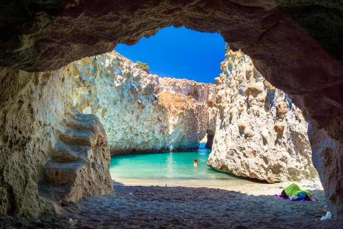 Una cueva con una playa con una persona en el agua.