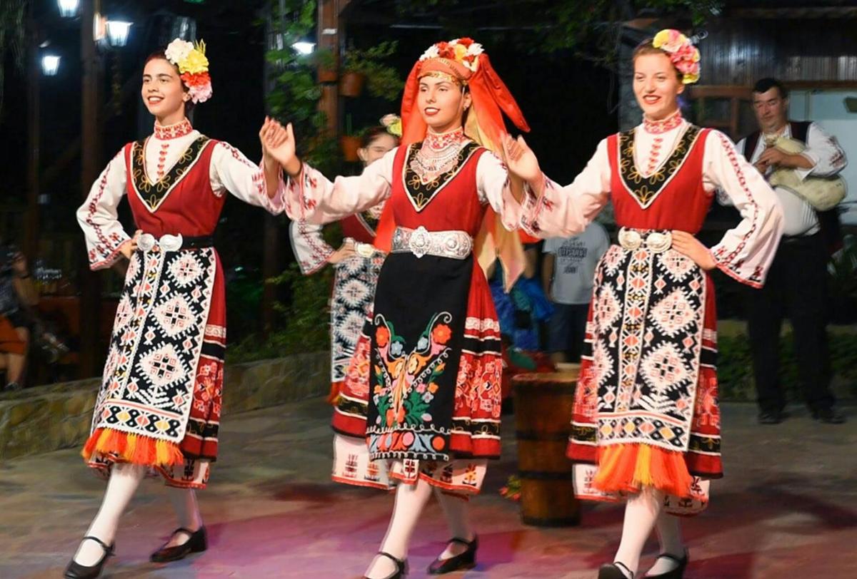 a group of three women in folk costumes dancing