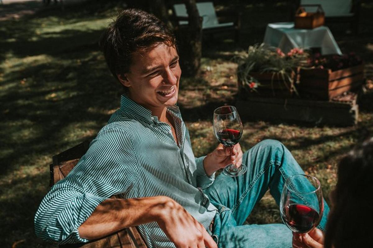um homem sentado em um banco segurando uma taça de vinho