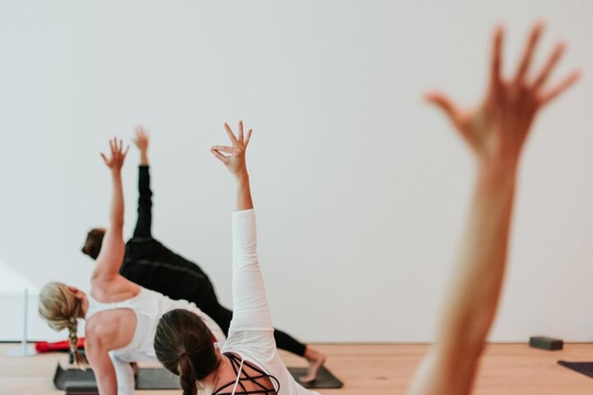 hai người phụ nữ trong lớp học pilates với hai tay giơ lên cao