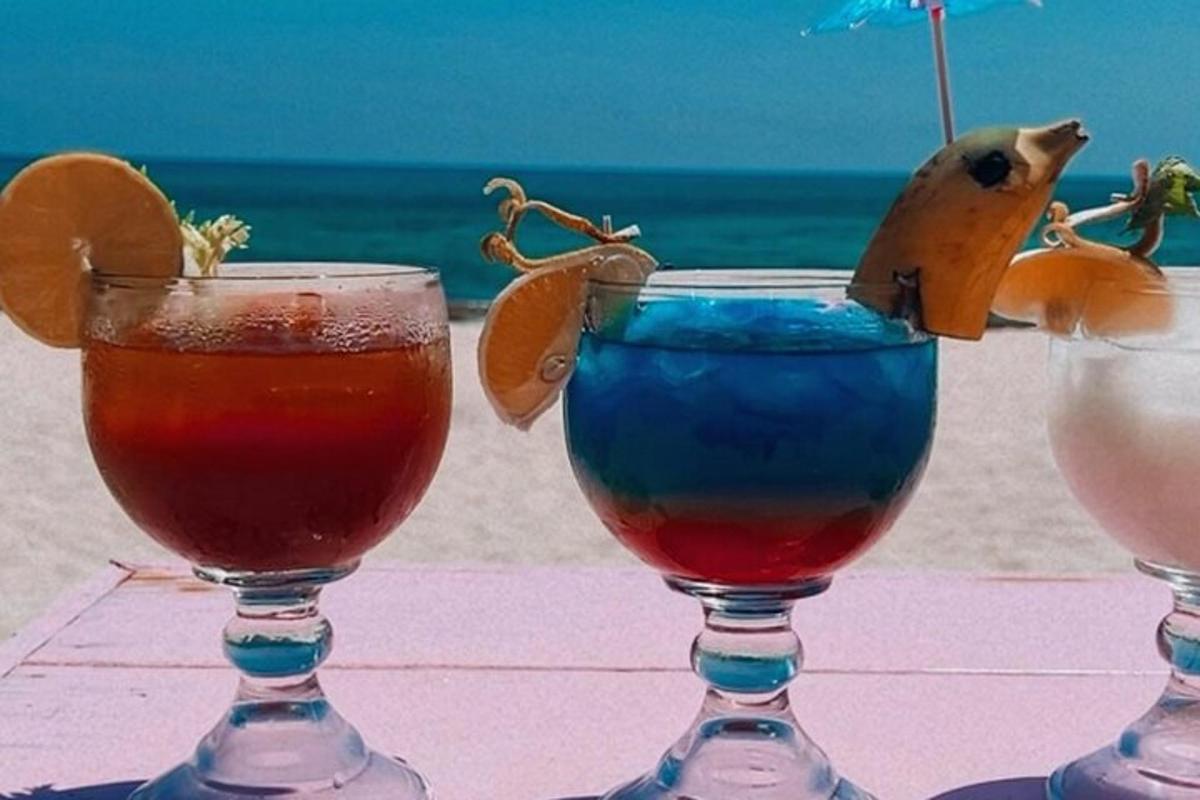 Dos copas de vino sobre una mesa cerca de la playa.