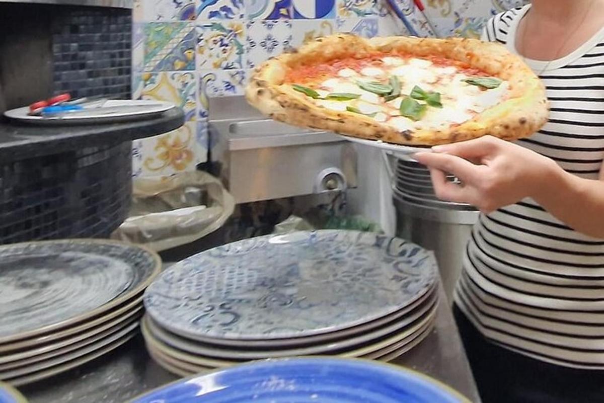 een vrouw die een pizza vasthoudt op een dienblad met borden