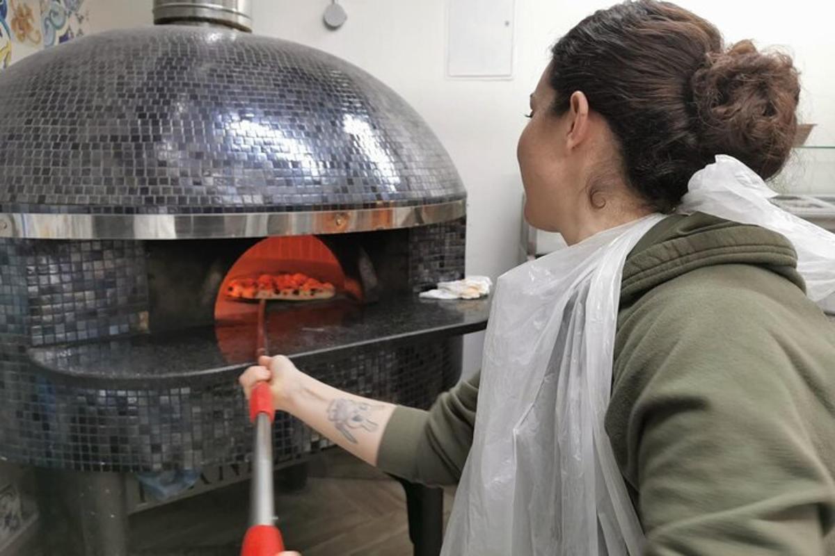 una dona posant una pizza al forn