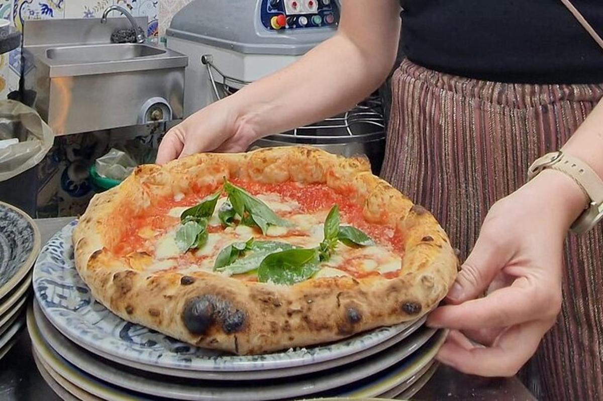 a woman holding a pizza on a stack of plates