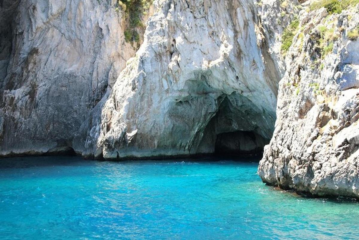 a cave in the side of a mountain with blue water