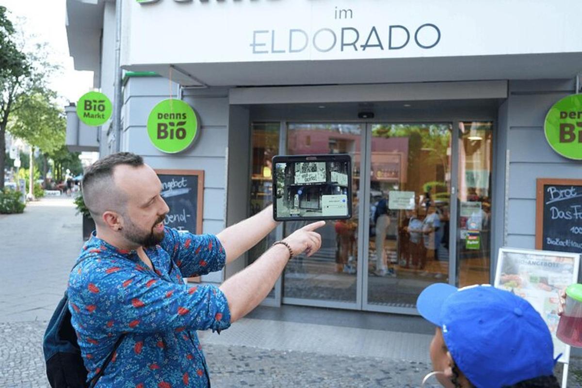 en mann som holder opp en mobiltelefon foran en butikk